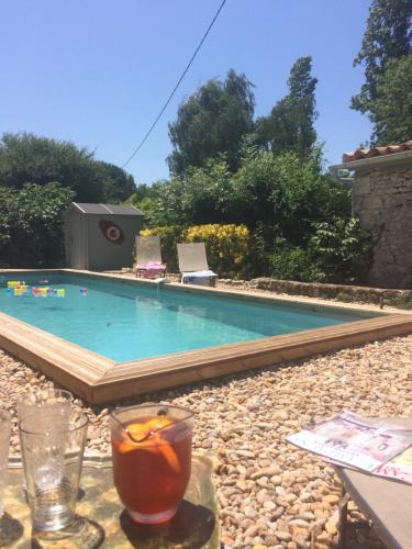 una bebida en una mesa junto a la piscina en Les Galineaux, en La Roquille