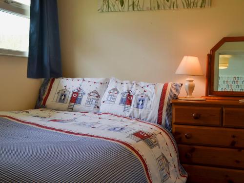 Schlafzimmer mit einem Bett, einer Kommode und einem Spiegel in der Unterkunft Poppy in Cromer