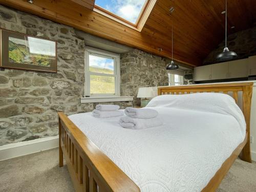 a bedroom with a large bed in a stone wall at Glacour Studio Cottage in Bridgend