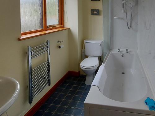 a bathroom with a tub and a toilet and a sink at Trellee in Budock Water