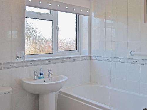 een witte badkamer met een wastafel en een bad bij Sea Breeze in Hopton on Sea