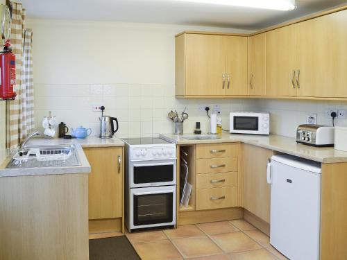 a kitchen with wooden cabinets and white appliances at The Gatehouse in Aberffraw