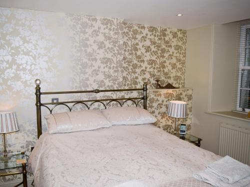 a bedroom with a large bed with floral wallpaper at Chaucers Nook in Wigan