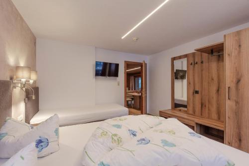 a bedroom with two beds and a tv on the wall at Hotel Garni Schönblick in Sölden