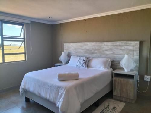 a bedroom with a large white bed and a window at Mourice Lodge in Sterkspruit