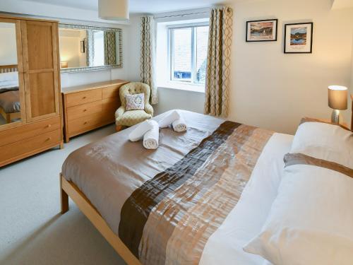 a bedroom with a bed and a chair and a window at 5 Balmoral House in Keswick