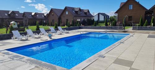 a swimming pool in a yard with chairs and a house at Domki La Plata in Łeba