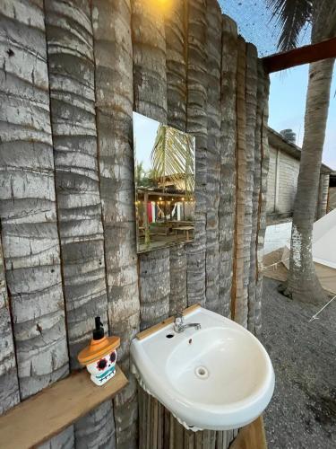 La salle de bains est pourvue d'un lavabo blanc et d'un mur en pierre. dans l'établissement Hostel Flakos, à Zihuatanejo