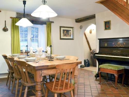 uma sala de jantar com uma mesa e um piano em The Old Smithy em Llanbadarn-fynydd