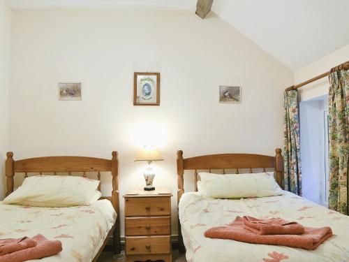 um quarto com 2 camas e uma mesa com um candeeiro em The Old Smithy em Llanbadarn-fynydd
