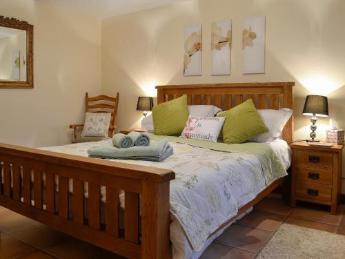 a bedroom with a wooden bed with green pillows at Ty Hir-bwlch Gwyn Farm Equestrian Centre in Fairbourne