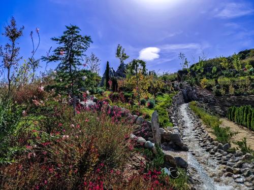 a garden on a hill with flowers and a stream at Verdisso Hotel & Restaurant in Demir Kapija