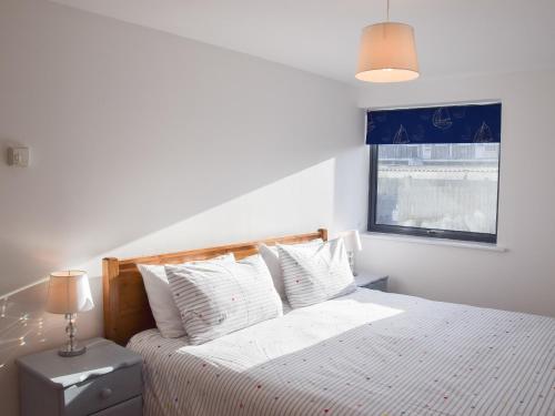 a bedroom with a bed with white sheets and a window at Sea Drift in West Bay