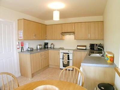 a kitchen with wooden cabinets and a table and chairs at Pennan Lodge - 26818 in Pennan