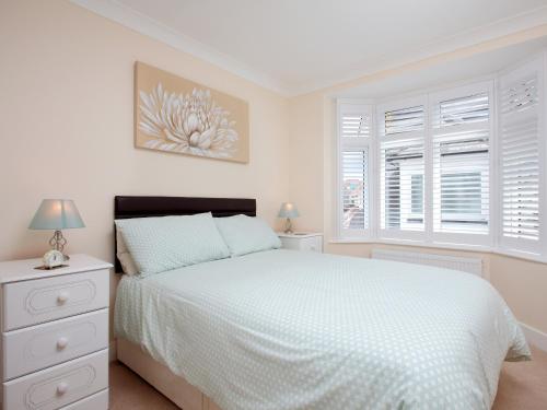 a white bedroom with a bed and two windows at The Avoncliffe Bournemouth in Southbourne