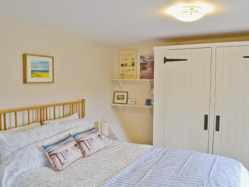 a bedroom with a bed with pink pillows at Briar Cottage in Lessingham