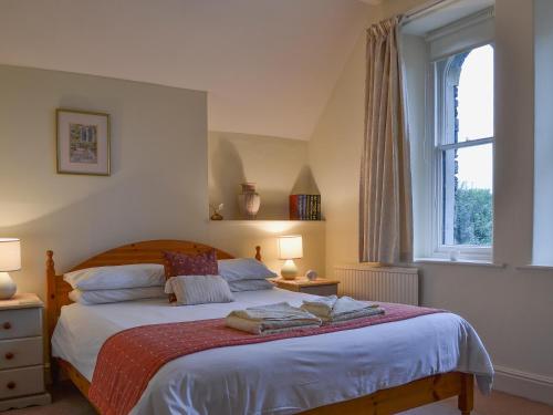um quarto com uma cama grande e uma janela em 1 School Cottage em Troutbeck Bridge