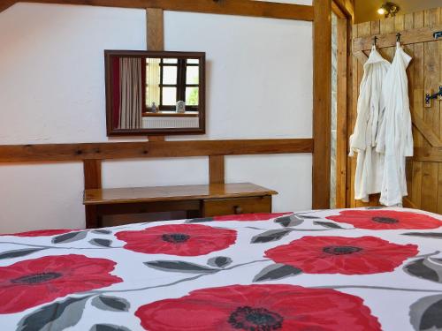 a bedroom with a bed with red flowers on it at The Coach House At Old Vicarage Cottage in Bettws-yn-Rhôs