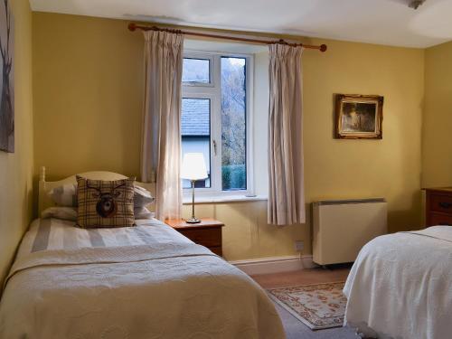 Stybarrow View Cottage في غلينريدنغ: غرفة نوم بسريرين ونافذة