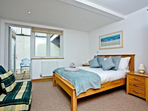 a bedroom with a bed and a chair and windows at Sea Glimpses in Saint Columb Minor
