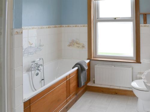ein Bad mit einer Badewanne, einem WC und einem Fenster in der Unterkunft Pembroke House in Happisburgh