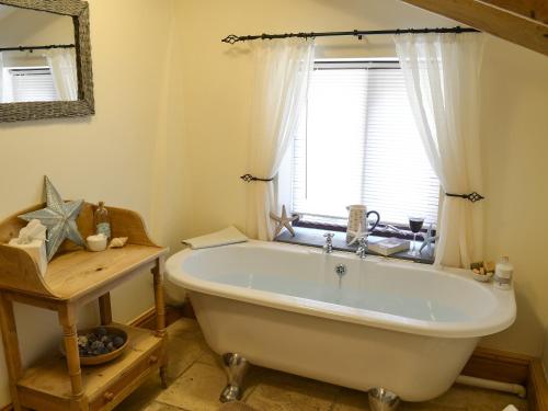 La salle de bains est pourvue d'une baignoire et d'une fenêtre. dans l'établissement The Old Wash House, à Pentewan
