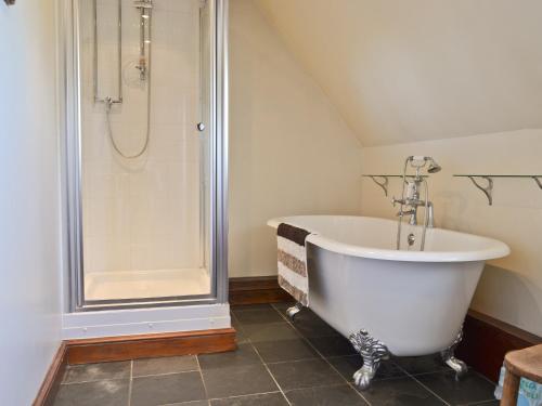 a white bath tub in a bathroom with a shower at Maytree Cottage in East Dereham