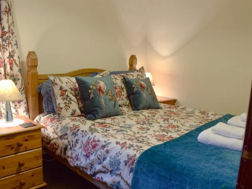 a bedroom with a bed and a dresser with a lamp at Hazel Cottage in Ambleside
