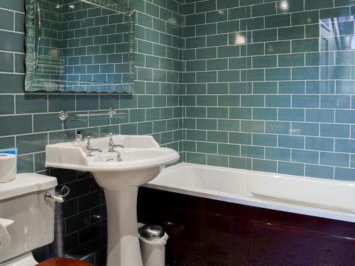 アンブルサイドにあるHazel Cottageの青いタイル張りのバスルーム(シンク、バスタブ付)