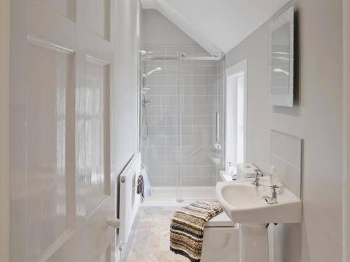 a white bathroom with a sink and a shower at Balcary Mews Cottage in Auchencairn