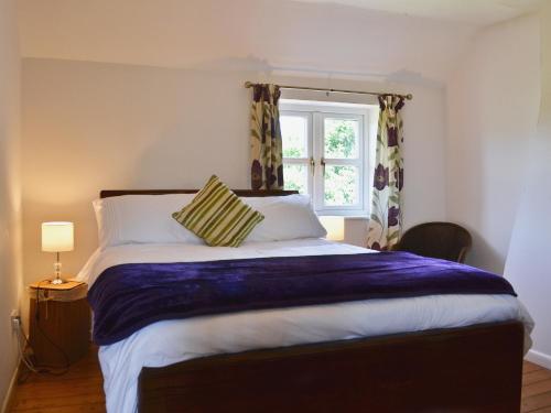 Schlafzimmer mit einem großen Bett und einem Fenster in der Unterkunft Chorlton Moss Cottage in Maer