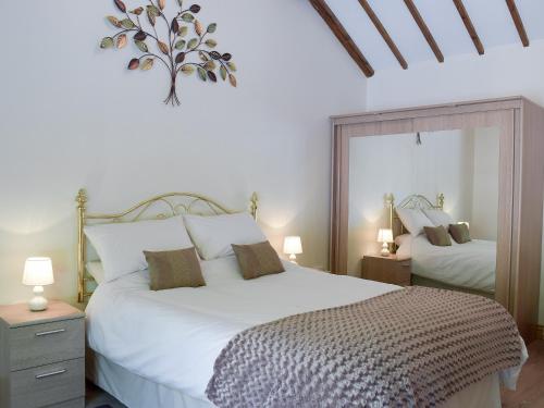 1 dormitorio con 1 cama blanca grande y 2 lámparas en The Coach House At Stable Cottage, en Derwydd