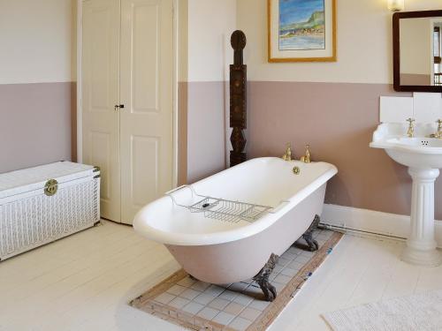 a bathroom with a white tub and a sink at Holly Lodge in Gilcrux