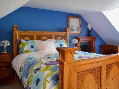 1 dormitorio con cama de madera y pared azul en Craigdarroch Cottage en Strathyre