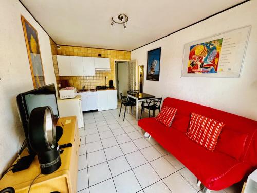 sala de estar con sofá rojo y cocina en Appartement familial labélisé centre du Racou, en Argelès-sur-Mer