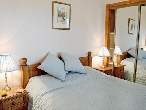 a bedroom with a bed with two lamps and a mirror at Larachan in Scarfskerry