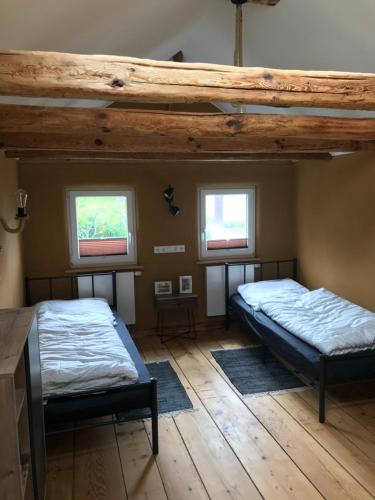 two beds in a room with two windows at Pension Schneidenbach in Reichenbach im Vogtland