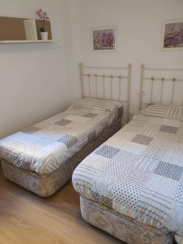 two beds in a room with white walls and wooden floors at Primera línea playa in Roquetas de Mar