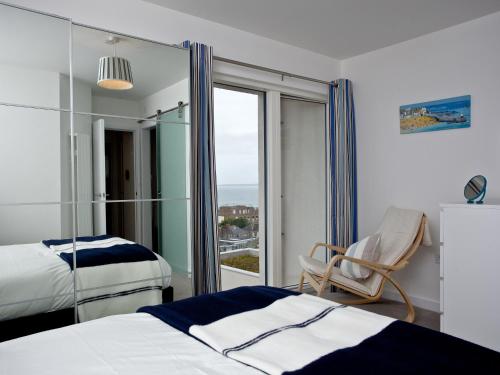 a bedroom with a bed and a chair and a window at Above Towan At 8 Quay Court in Newquay