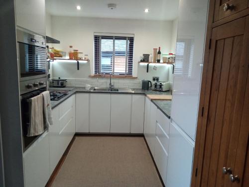 uma cozinha com armários brancos e um lavatório em Charming lodge cosy comfortable ideal location em Blairgowrie