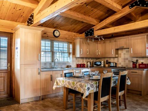 uma cozinha com uma mesa e cadeiras e tectos em madeira em Lake View Lodges - 25073 em Leake Common Side