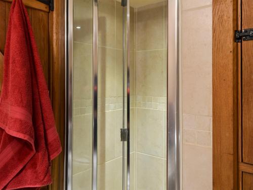 La salle de bains est pourvue d'une douche avec une porte en verre. dans l'établissement The Cowstall, à Framfield