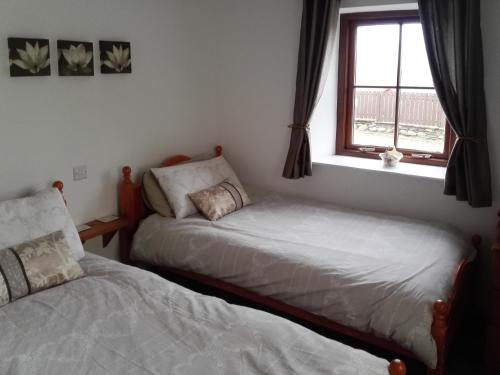 a bedroom with two beds next to a window at Jenlea Cottage in Grizebeck