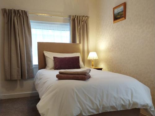 a bedroom with a large white bed with a window at Knock School Cottage in Monreith