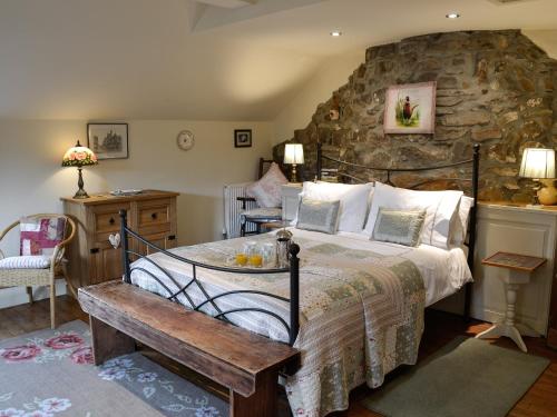 a bedroom with a bed and a stone wall at Bryn Dedwydd Cottage in Llanferres