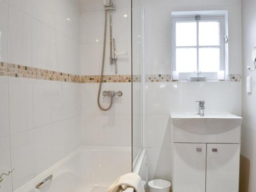 a white bathroom with a shower and a sink at Temple House West in Drumnadrochit