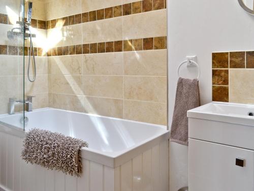 a bathroom with a tub and a sink at The Dairy in Arlingham