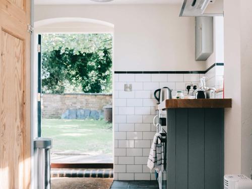 a kitchen with a green and white tiled wall at Southfield Cottage in Braunston