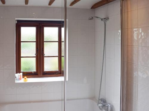 a bathroom with a shower and a tub and a window at The Old Bakery in Wendover