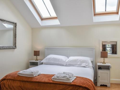 a bedroom with a bed with white sheets and pillows at Oak Tree Cottage in Otterburn